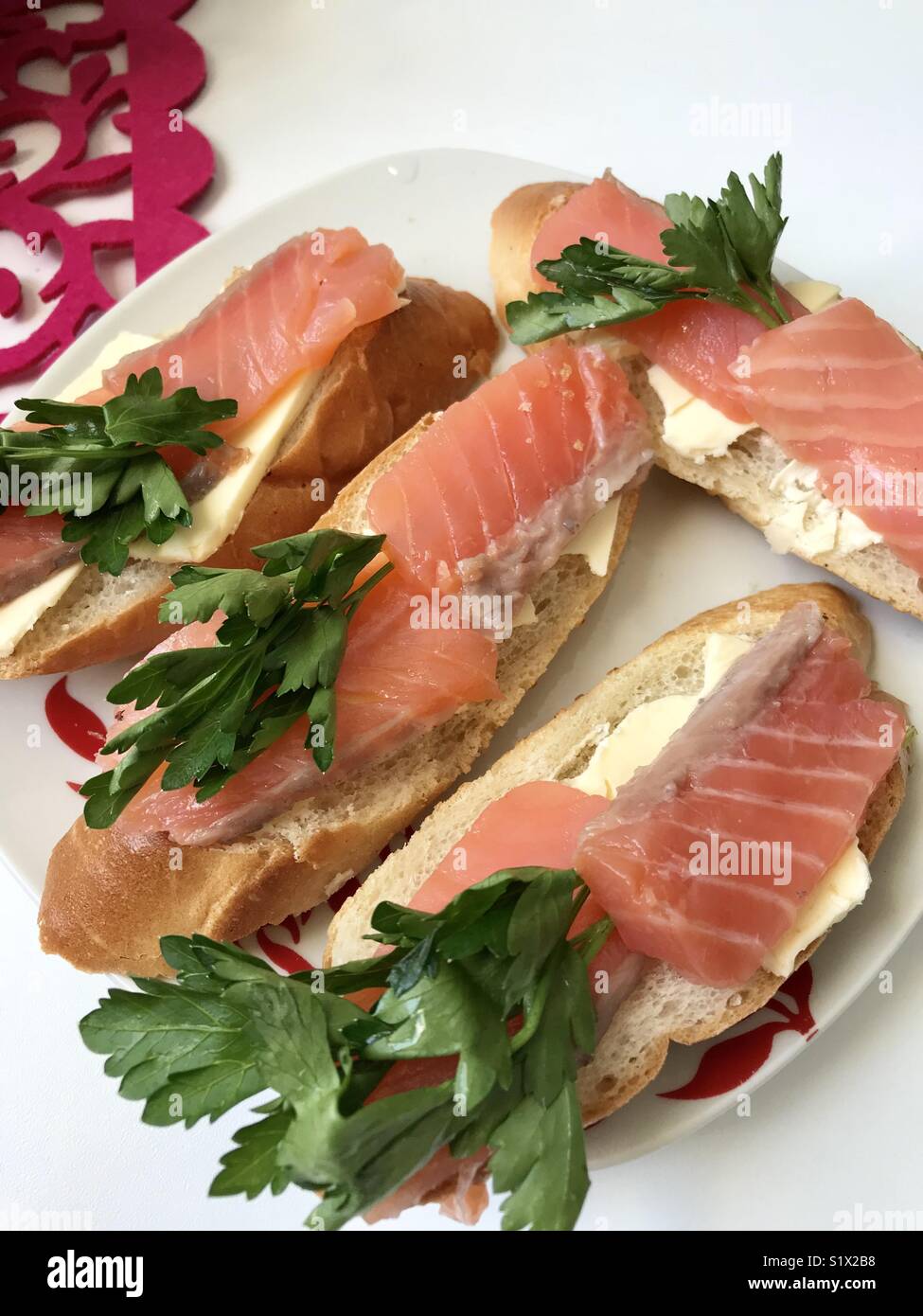 Sandwiches mit Lachs und Grüns. Stücke von Fisch sind auf einem Brot, Baguette, geölt. Mit frischer Petersilie dekoriert. Stockfoto