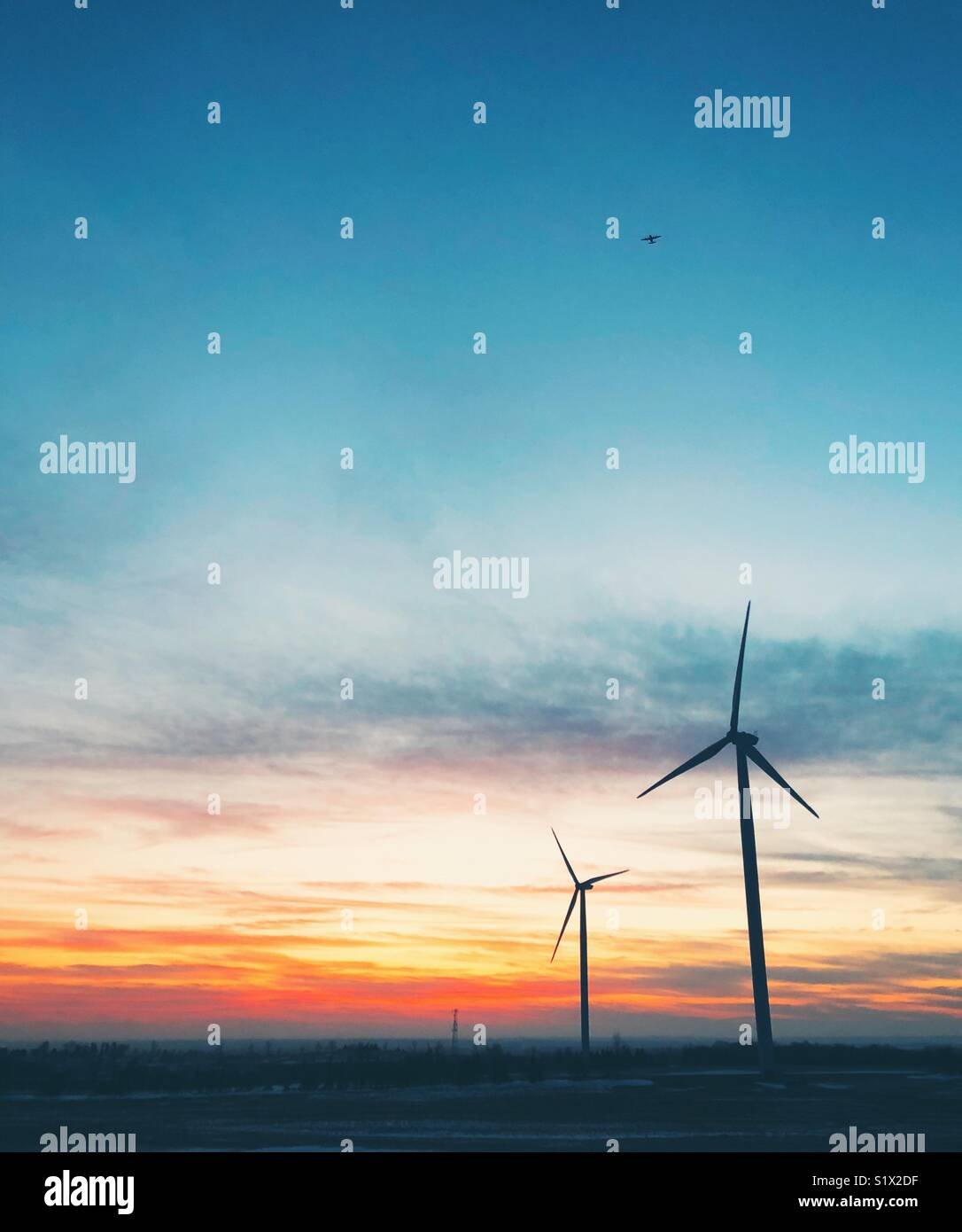 Zwei der insgesamt neun ZEP Windpark Ganaraska Windräder im Sonnenuntergang mit dem Flugzeug in der Entfernung in der Nähe von Portland, Ontario, Kanada - Smartphone-aufgenommenes Stockfoto