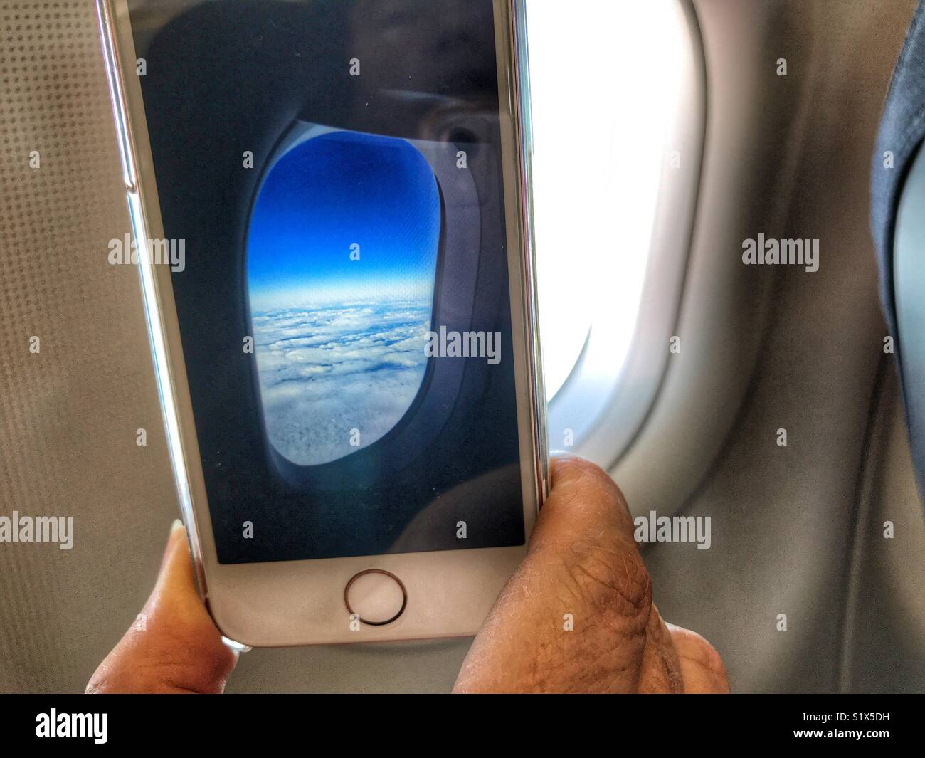 Ein Smartphone in der Hand, ein Foto aus dem Fenster eines Flugzeuges Stockfoto