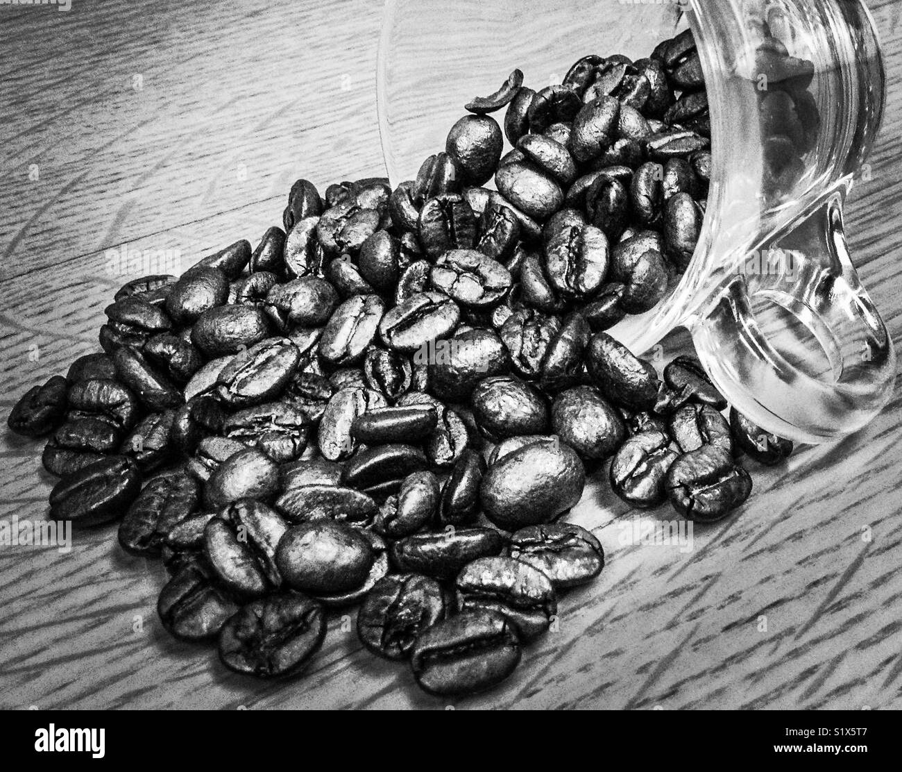Verschüttete Kaffeebohnen aus Glas Becher Stockfoto