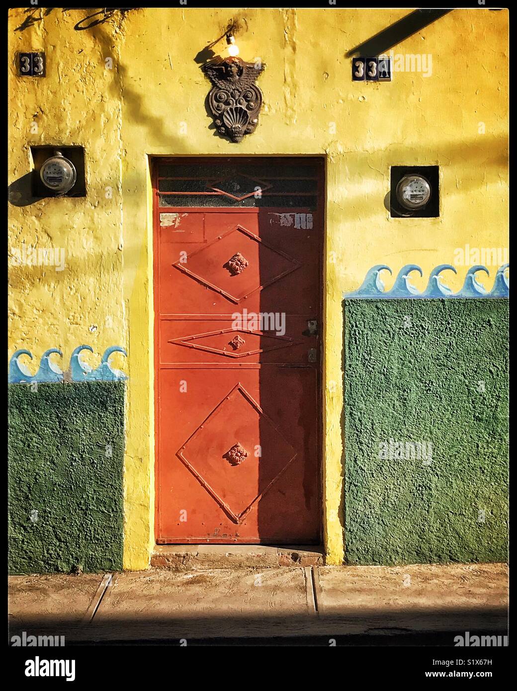 Eine Tür und individuell bemalte Wand werden durch die Morgensonne in Ajijic, Mexiko hervorgehoben. Stockfoto