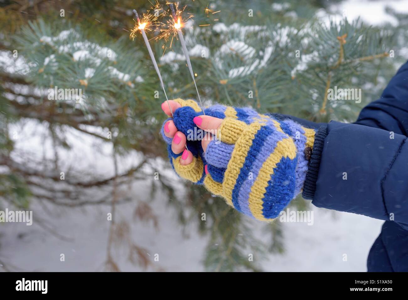 Frau in hellen fingerlose Handschuhe holding Wunderkerzen an einem Wintertag (nur Hände) Stockfoto