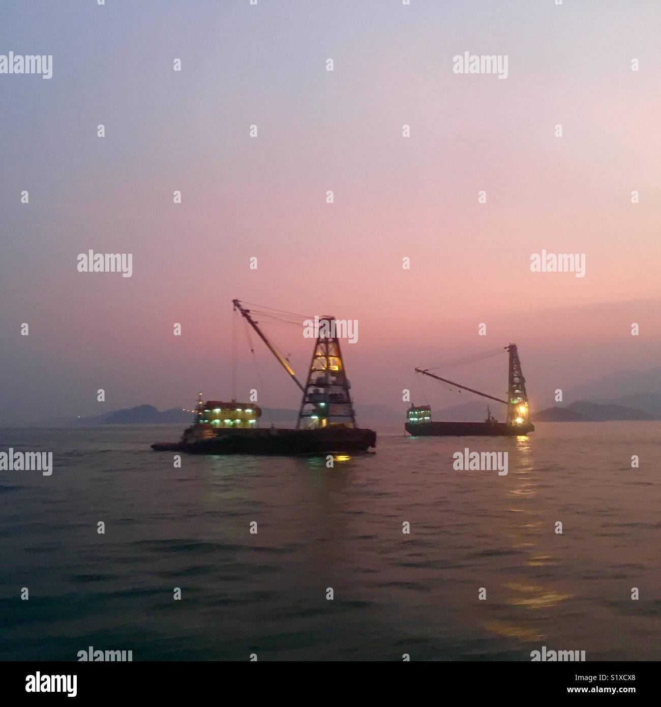 Kommerzielle Boote bei Dämmerung in Hongkong Stockfoto