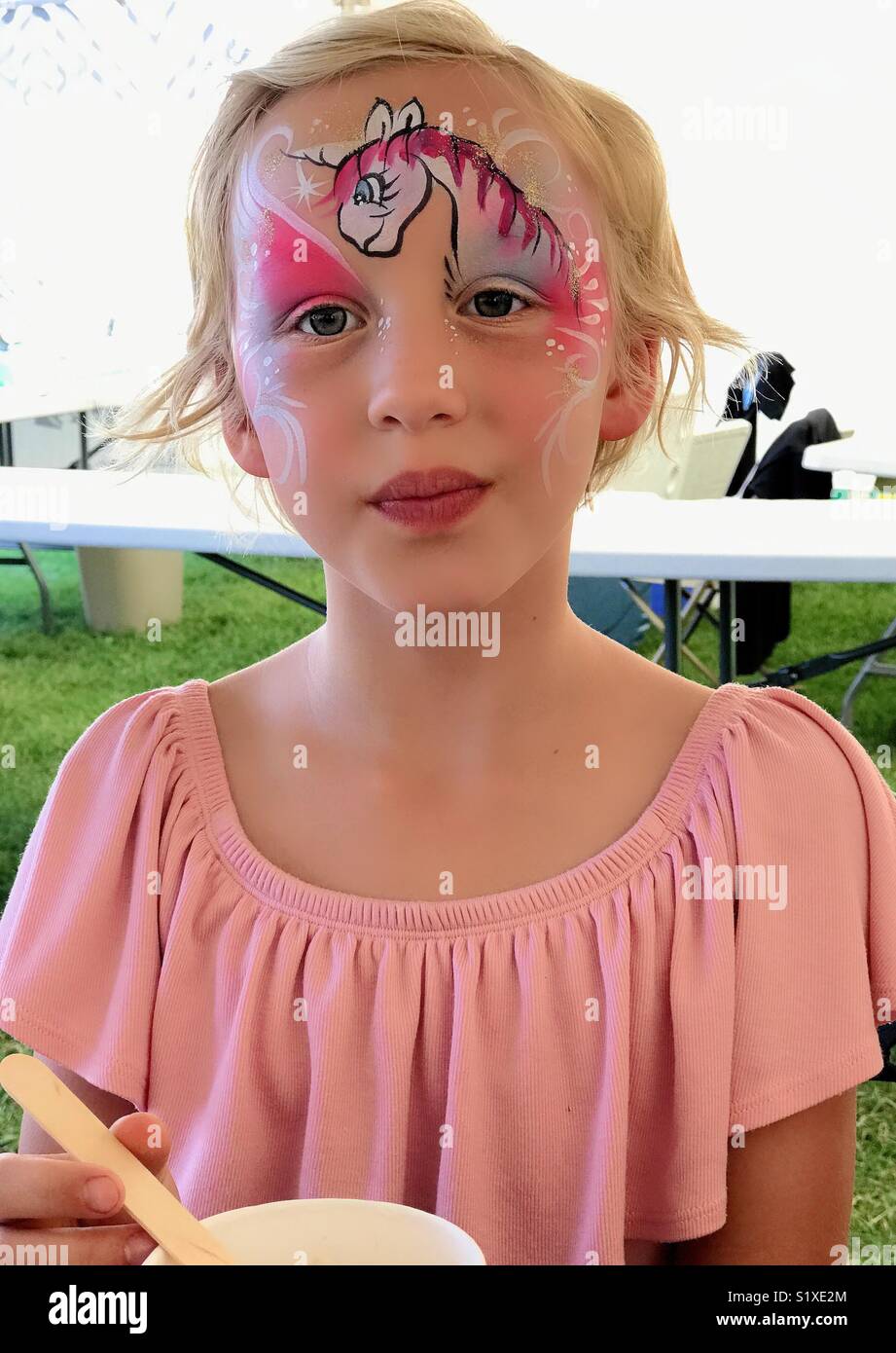 Ein Mädchen mit Gesicht Farbe auf einer Messe. - Smartphone-aufgenommenes Stockfoto