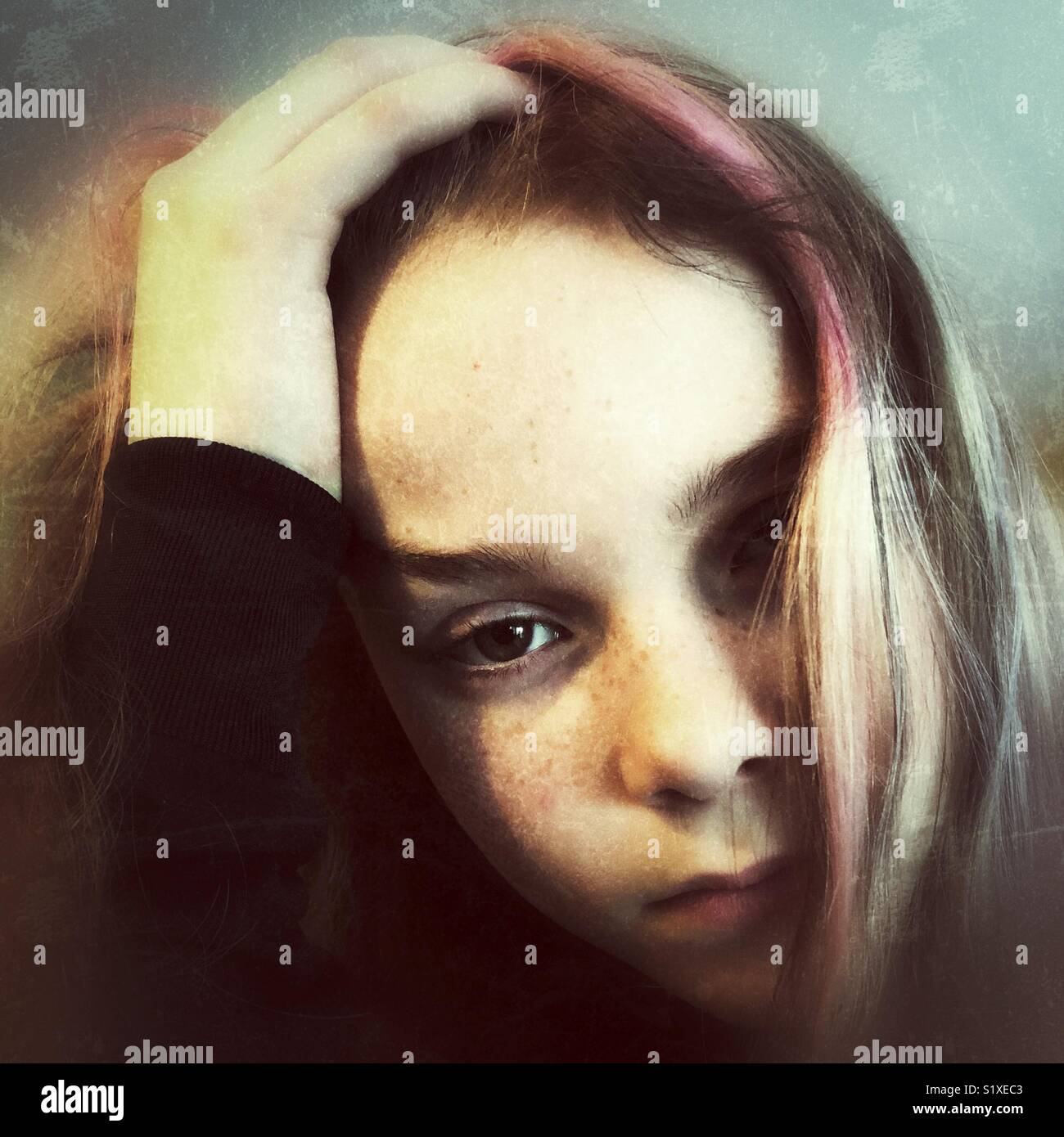 Portrait von traurigen Mädchen mit Hand auf den Kopf in die Kamera schauen, kreativ verarbeitet - Smartphone-aufgenommenes Stockfoto