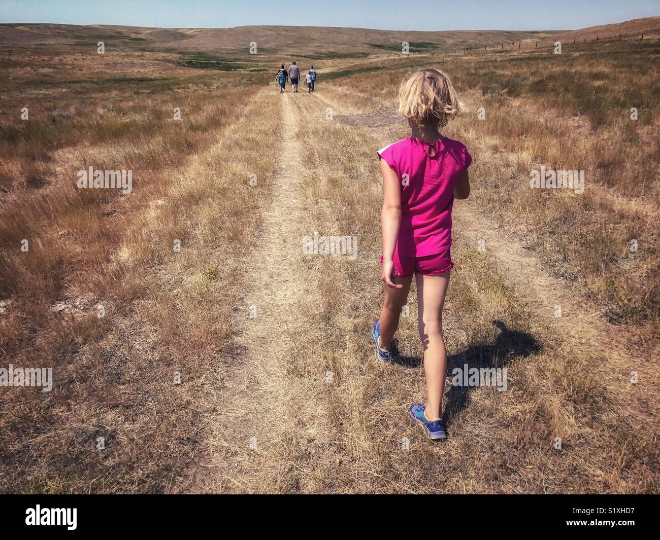 Ein Mädchen Wanderungen munter durch die Wiesen des südlichen Saskatchewan, Kanada, bis zu ihrer Familie zu fangen. Stockfoto