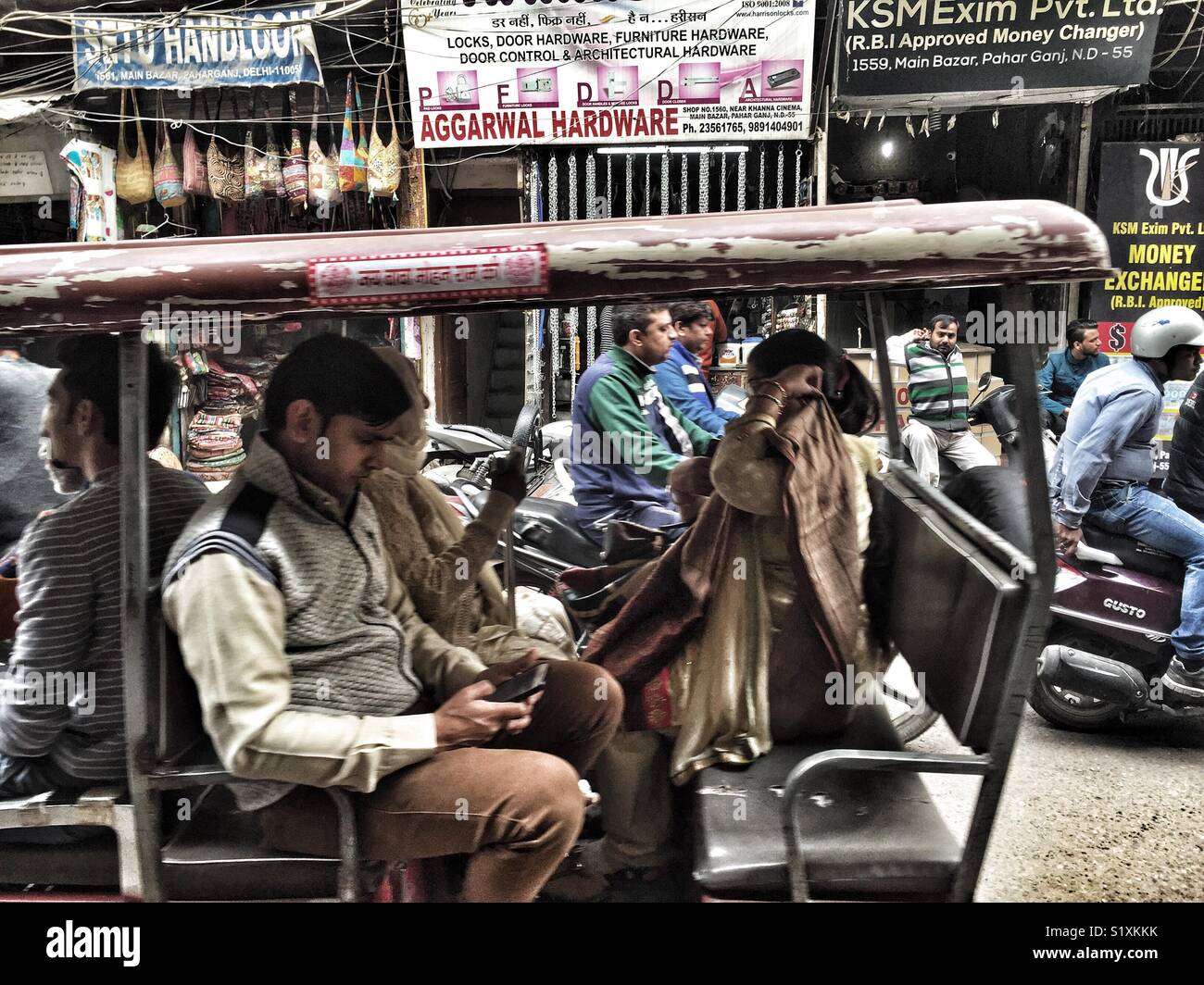Die Menschen reisen in einer Rikscha in Paharganj in Delhi, Indien - Smartphone-aufgenommenes Stockfoto