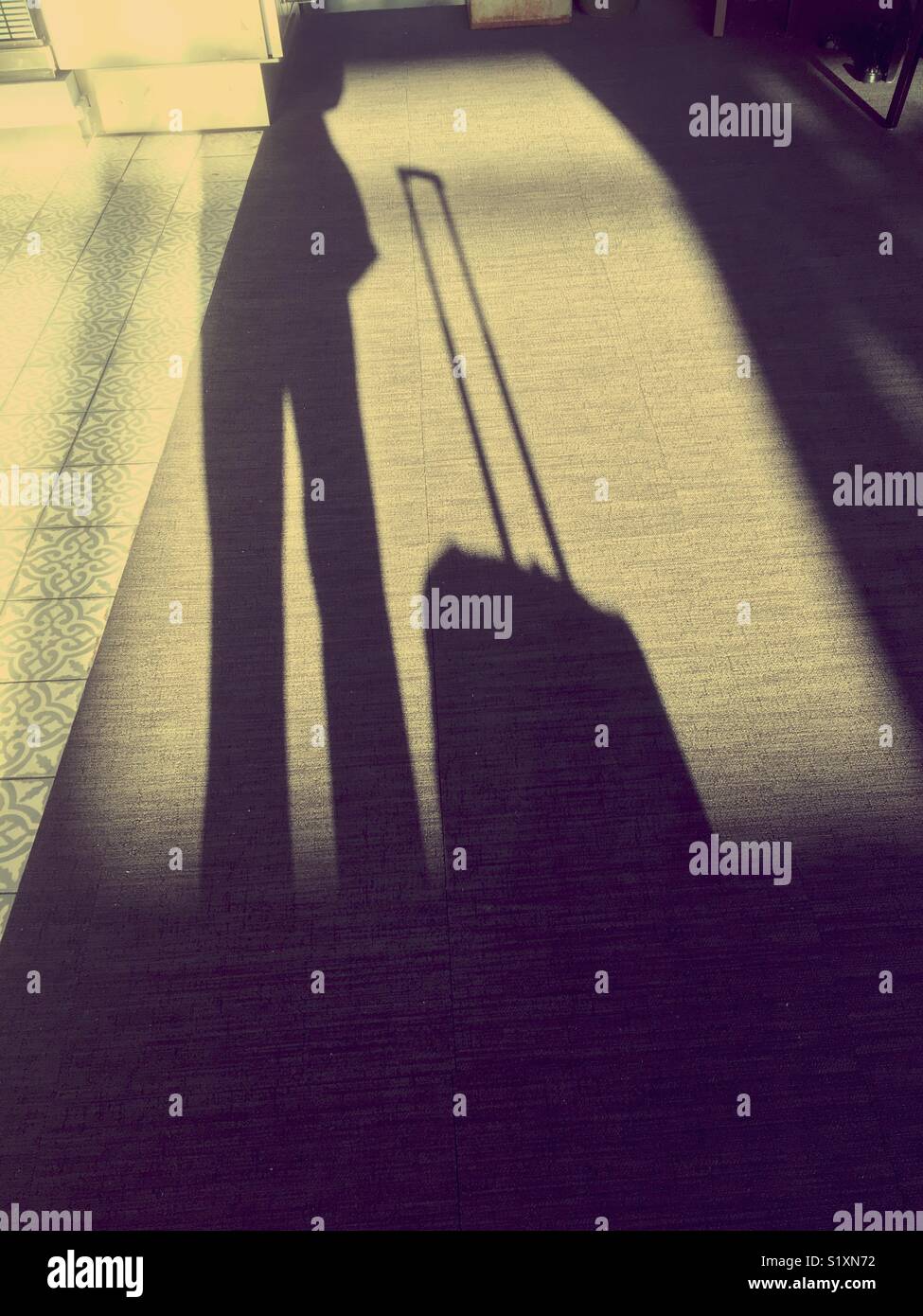 Geschäftsmann Schatten mit Gepäck am Flughafen warten - Smartphone-aufgenommenes Stockfoto