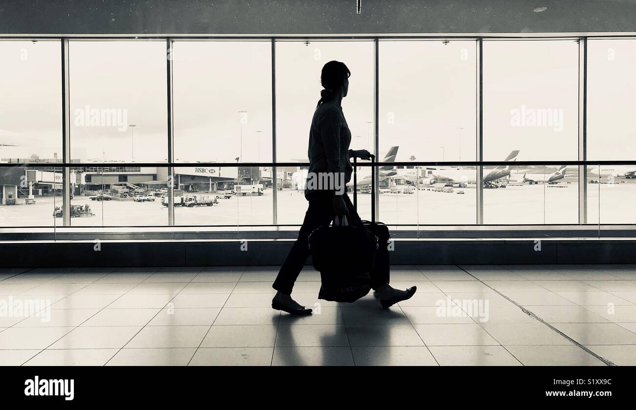 Eine Person zu Fuß durch einen Flughafen und Flugzeuge auf dem Vorfeld - Smartphone-aufgenommenes Stockfoto