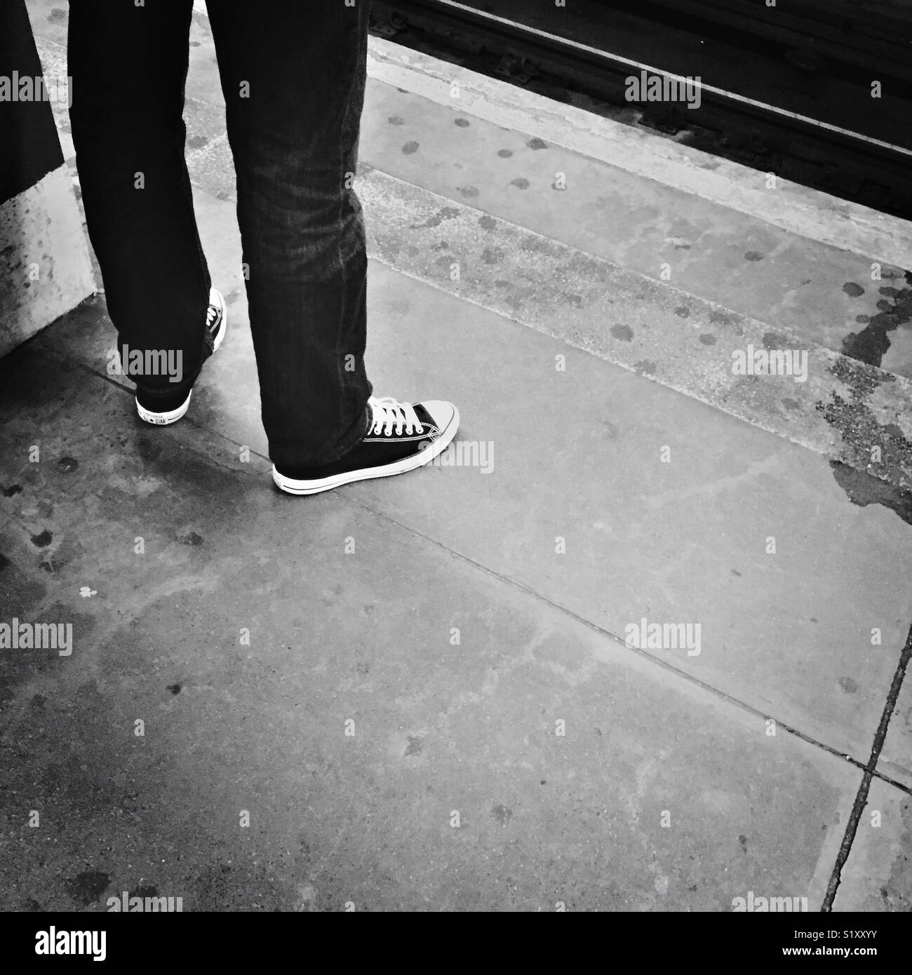 Ein Mann in Jeans und Converse Chuck Taylor sneakers steht auf einem New York City U-Plattform, Februar 2018. Stockfoto
