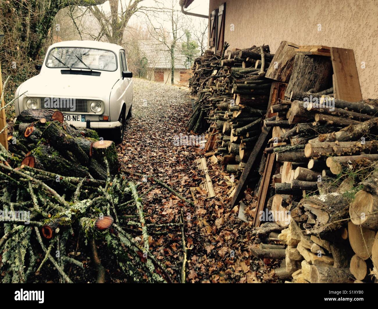 Gespeichert Brennholz von Schnitt und fällten Bäume, Gestapelt und bereit zum Brennen außerhalb eines französischen Haus auf dem Land. Frankreich. Renault 4L Auto geparkt ist - Smartphone-aufgenommenes Stockfoto