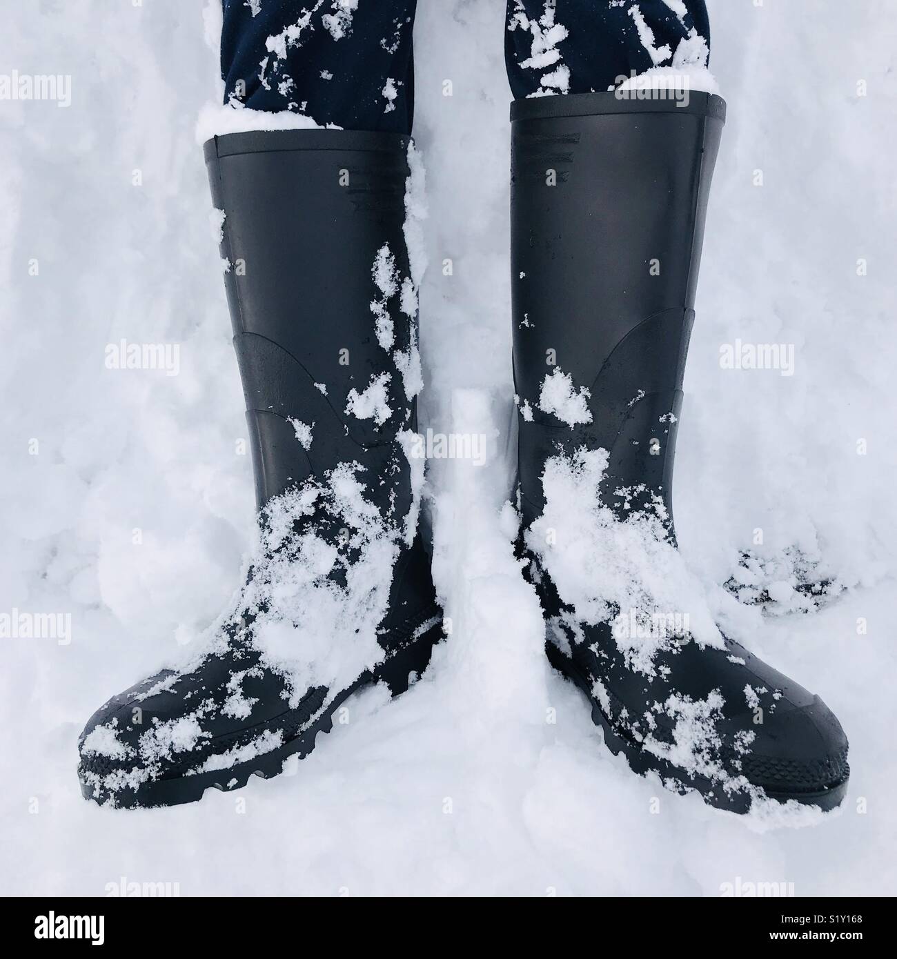 Schwarze Gummistiefel im Schnee Stockfoto