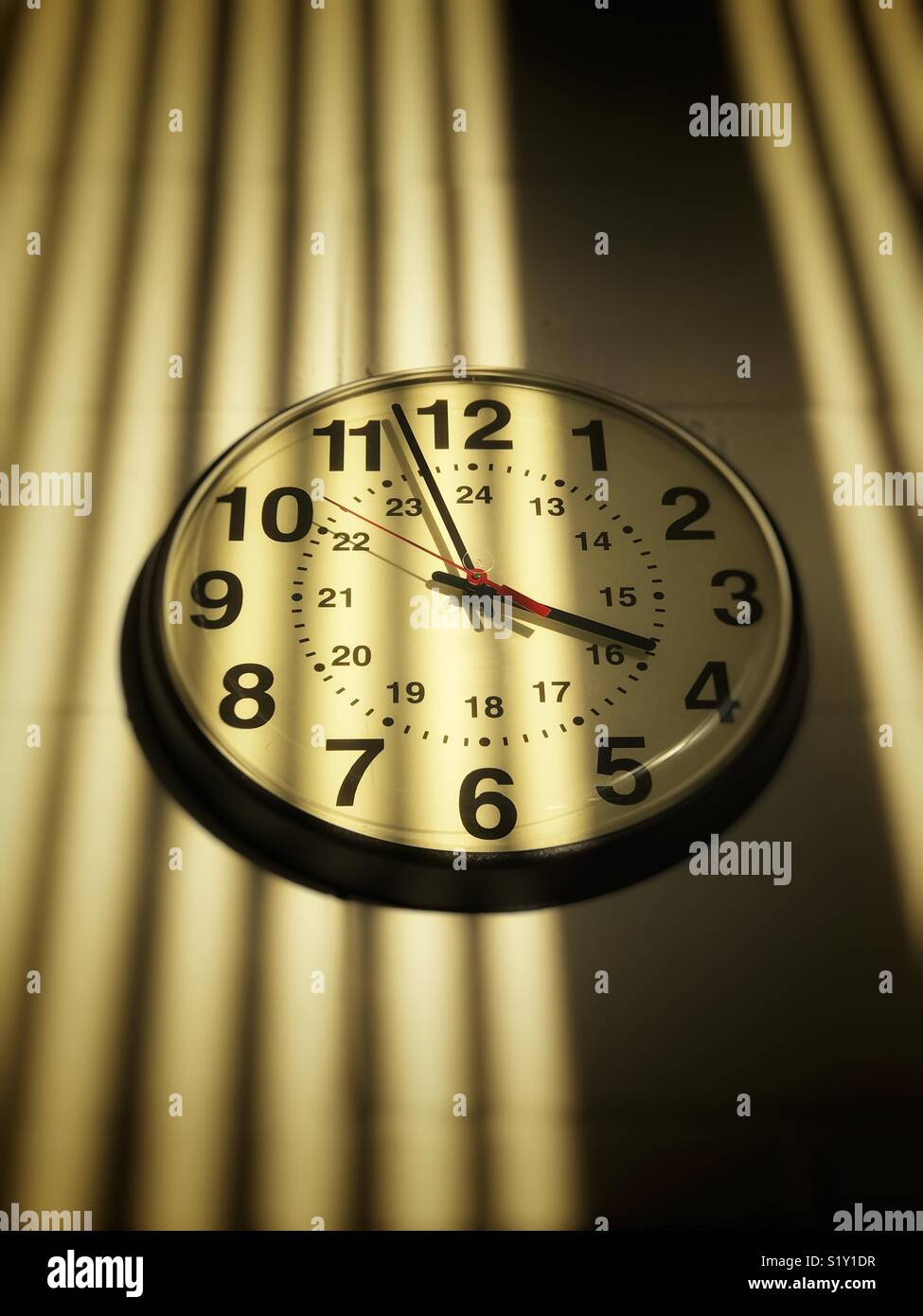 Institutionelle Uhr an der Wand mit Schatten - Smartphone-aufgenommenes Stockfoto