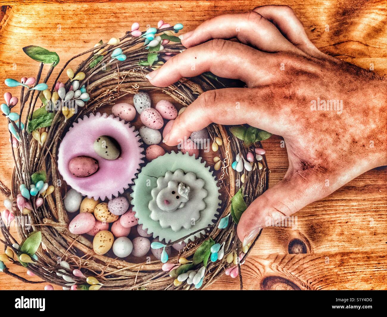 Ostern behandelt. Erreichen für einen gefrorenen Cupcake - Smartphone-aufgenommenes Stockfoto