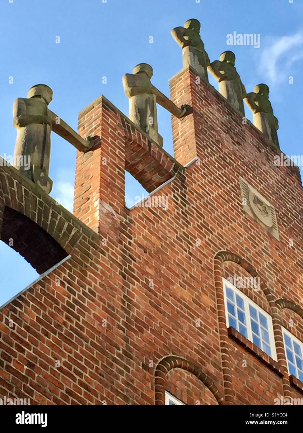 Red brick House Giebel mit Statuen am Eingang der Böttcherstraße, Bremen, Deutschland. Das Haus der Sieben Faulen Brüder mit Figuren auf einem stufengiebel durch Aloys Röhr in Münster. Stockfoto