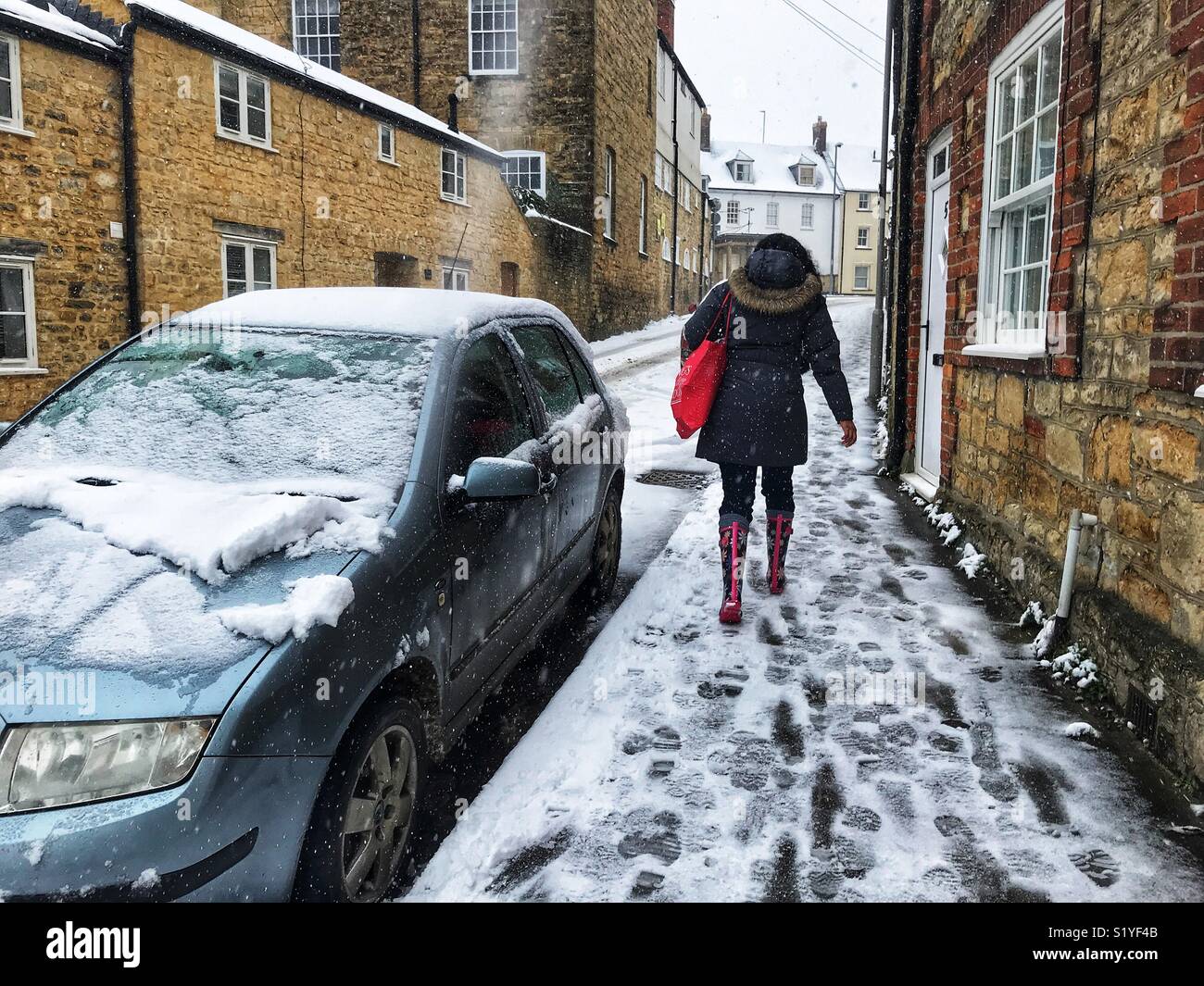 De, Wetter, Sherbourne, Dorset. Frau zu Fuß durch den Schnee im oberen Billig Straße wie die so genannte Mini Tier aus dem Osten eine andere eisige Blast im Süden Westen bringt. Stockfoto