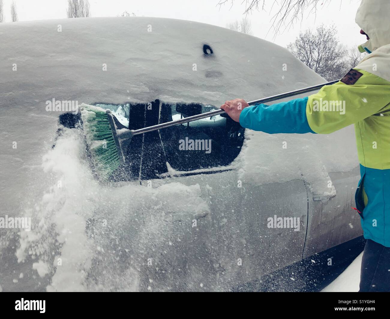Junger Mann Reinigung Schnee auf dem Auto Stockfoto