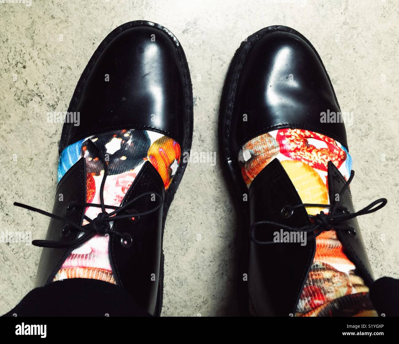 Füße in Socken mit Donuts und Fancy schwarze Schuhe Stockfoto