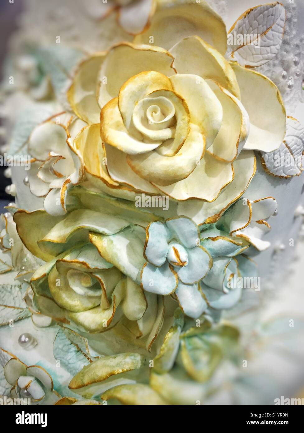 Weiße Blüten mit Gold Trim auf einem Kuchen Stockfoto
