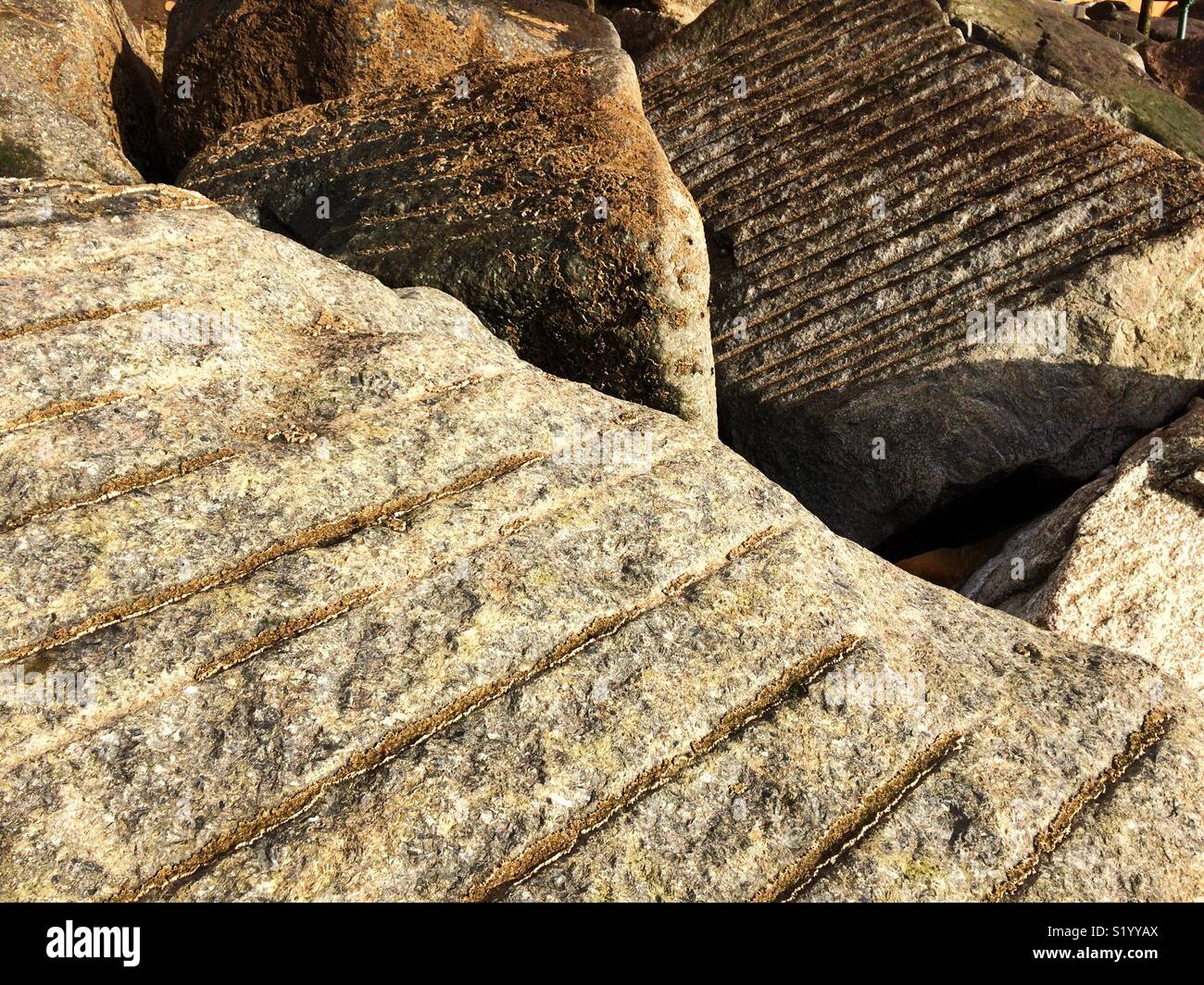 Riesige Granitblöcke sind für den Küstenschutz auf der Jurassic Coast in der Nähe von Sidmouth verwendet. Der Granit wurde von Hand geschnitten. Stockfoto