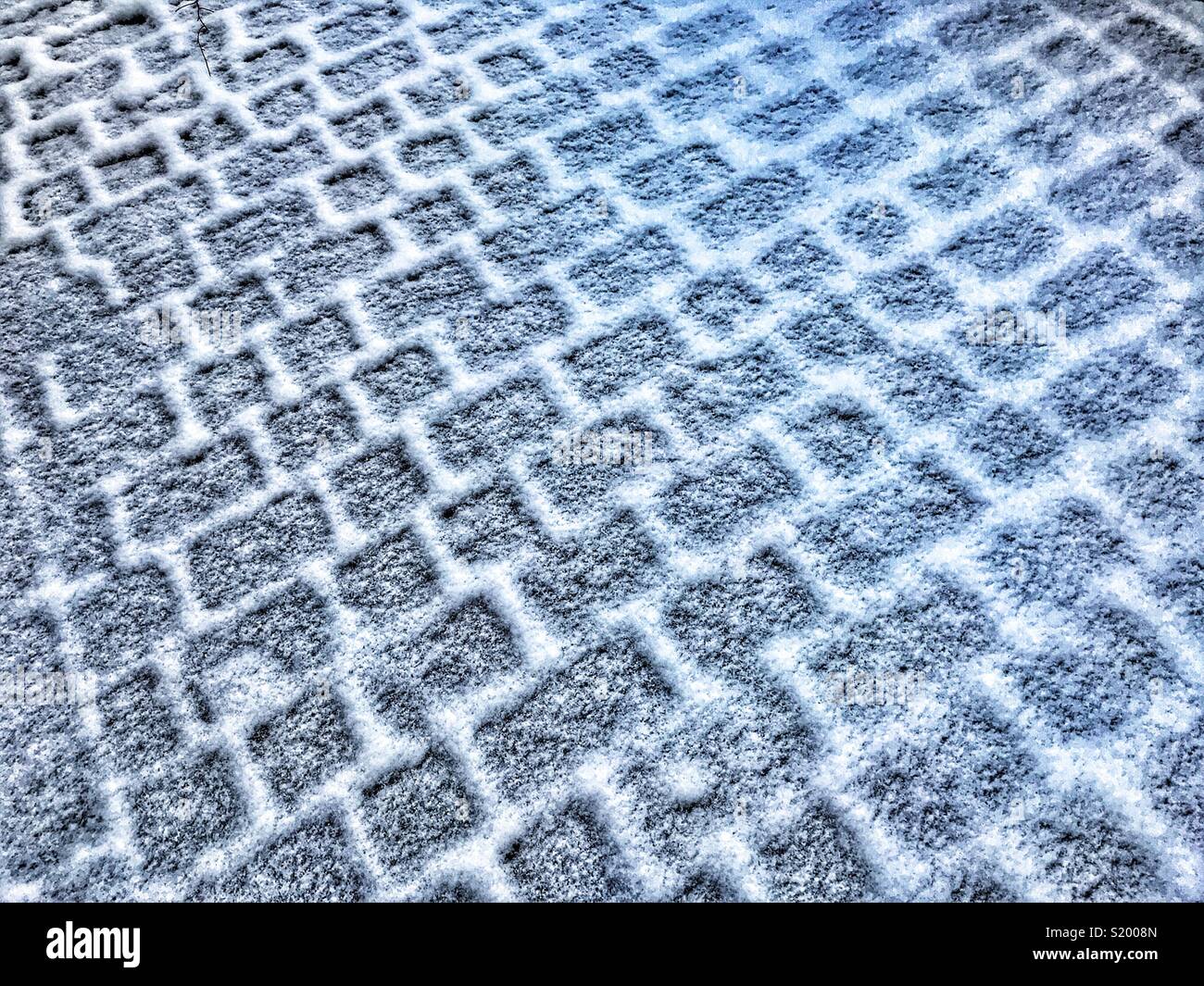 Abstraktes Muster aus Schnee auf einem Fliesen- Pflaster - Smartphone-aufgenommenes Stockfoto