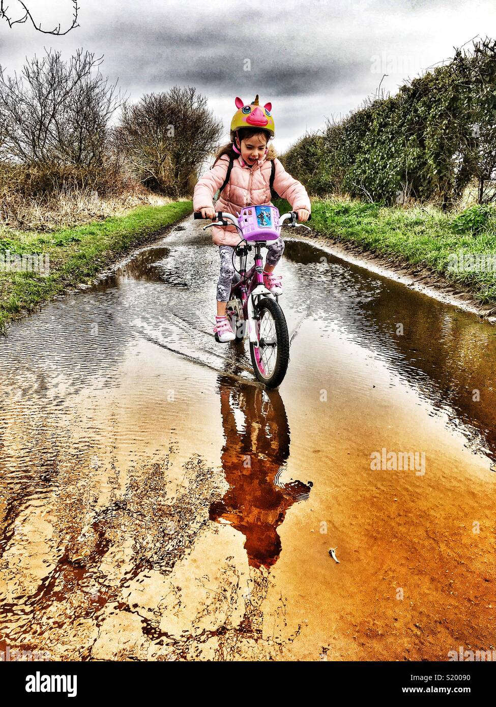 Mädchen Fahrrad obwohl große Pfütze - Smartphone-aufgenommenes Stockfoto