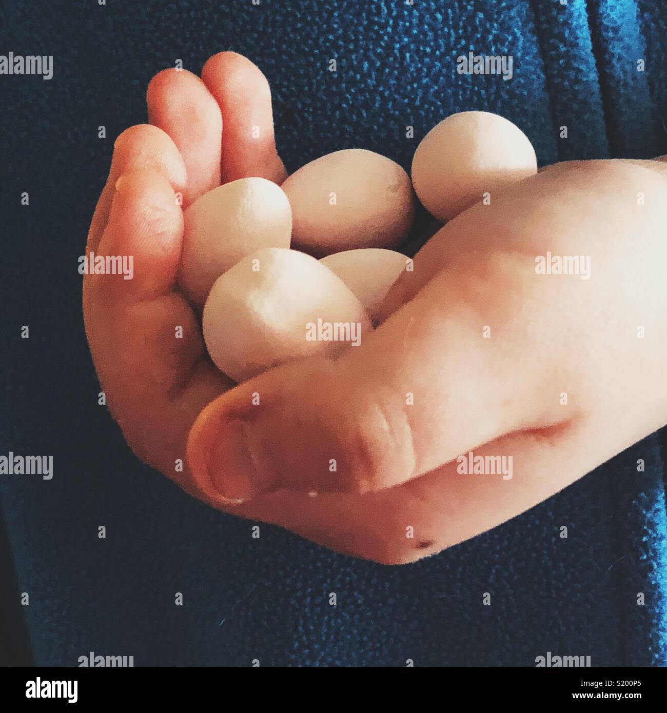 Child's Hand, die Süßigkeit beschichtetes Schokolade Ostereier Stockfoto