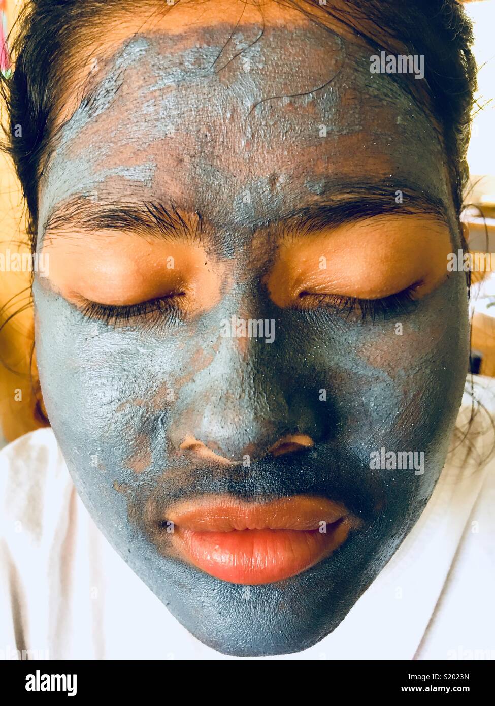 Mädchen mit blauen Schlammpackung Gesichtsmaske Stockfoto