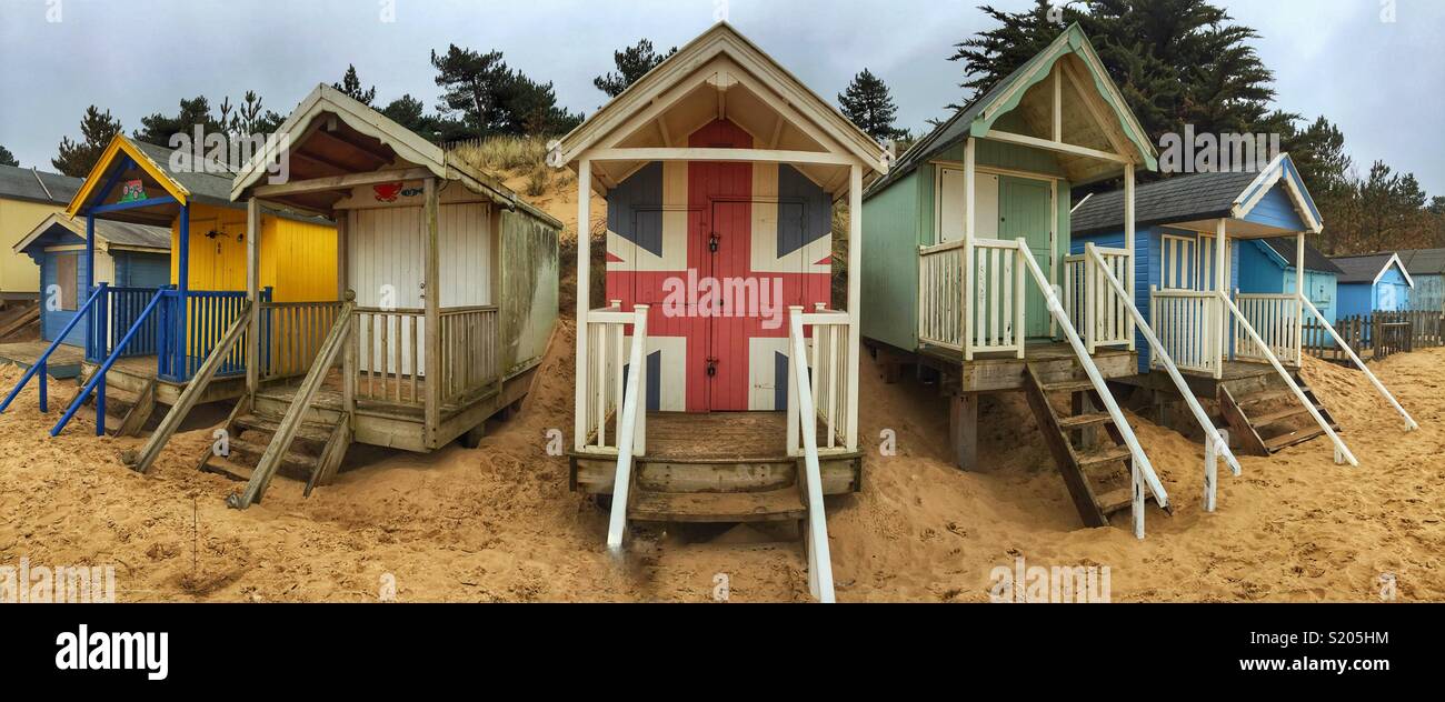 Bunte badehäuschen an einem Sandstrand an der Brunnen neben dem Meer in Norfolk, Großbritannien mit einem Union Jack Flagge auf lackierten Stockfoto