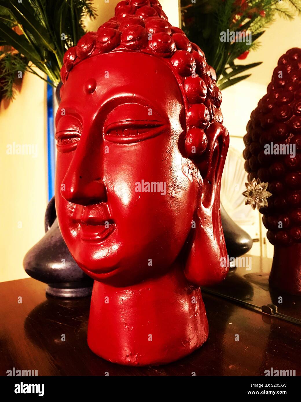 Tibetischen Dekor - Red Head Statue auf Kamin Mantel mit Vase und Blumen Stockfoto