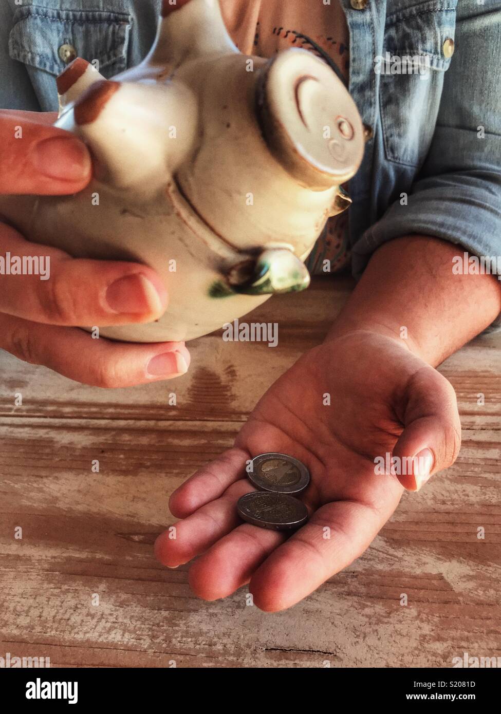 Tausendjährige Frau Schütteln der Geld aus einem Sparschwein. - Smartphone-aufgenommenes Stockfoto