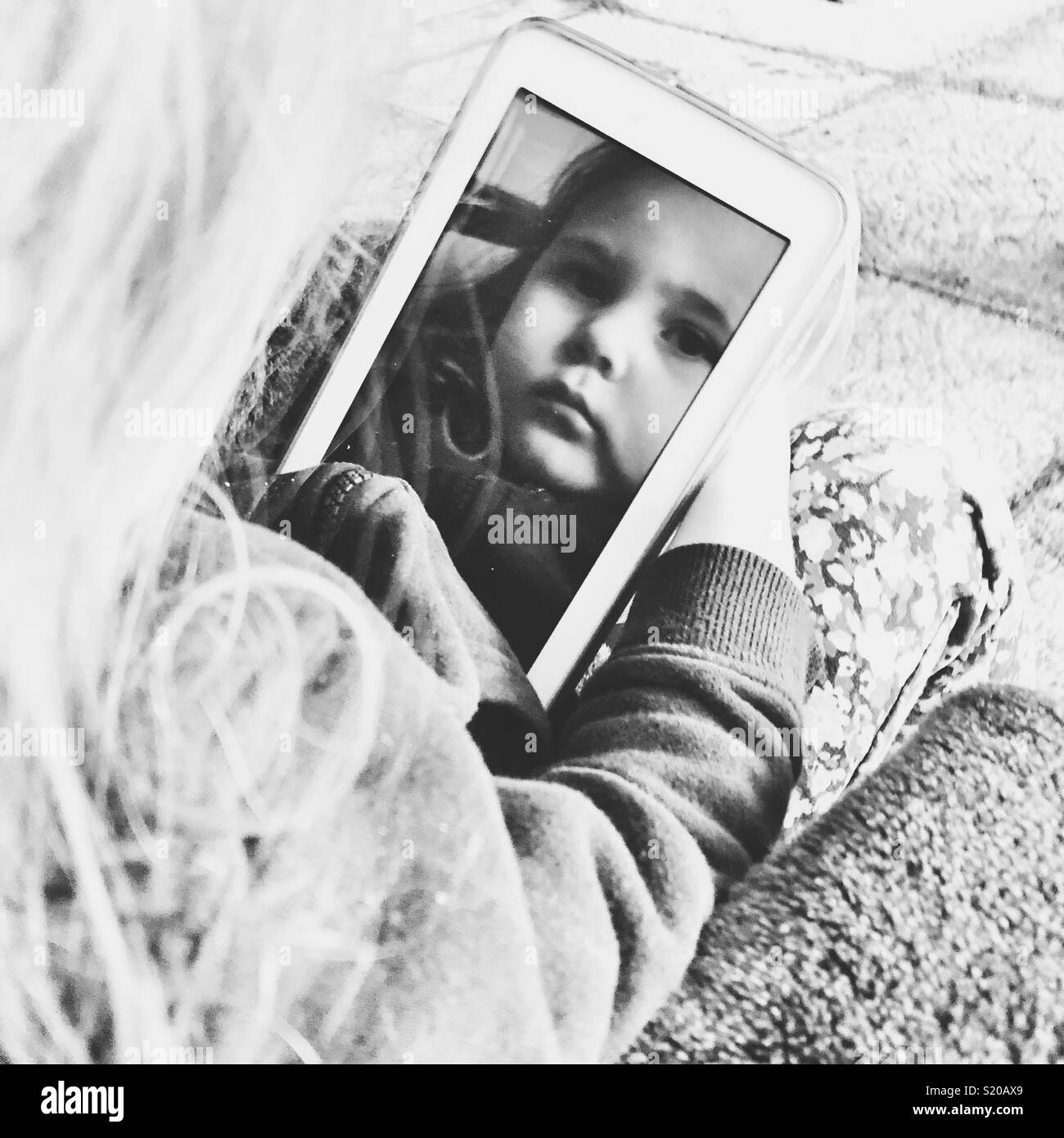 Schwarz-weiß-Bild des Sehens junge Mädchen Reflexion in der Tablette, während Sie ihn gedrückt halten Stockfoto