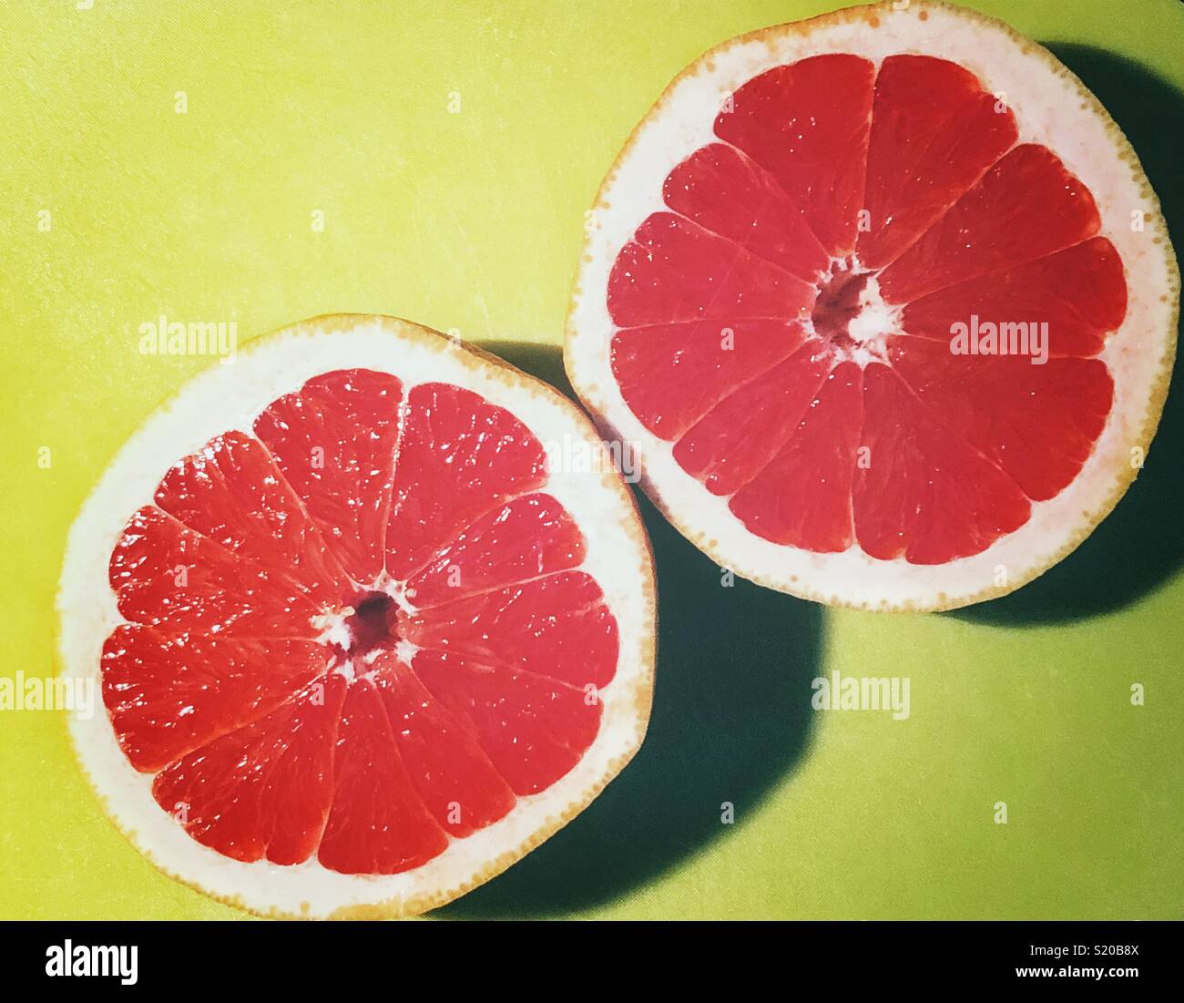 Saftig, Rubinrote Grapefruit halbiert auf ein helles Grün Schneidebrett - Smartphone-aufgenommenes Stockfoto
