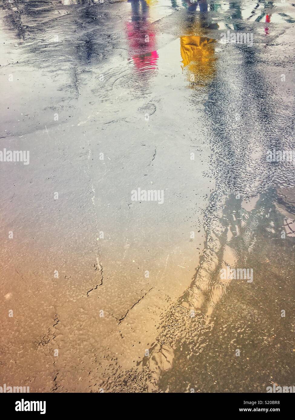 Die Reflexion von Menschen in regenmäntel und der Schatten der Kings Island Eiffelturm Replikat in Regen Pfützen. Stockfoto