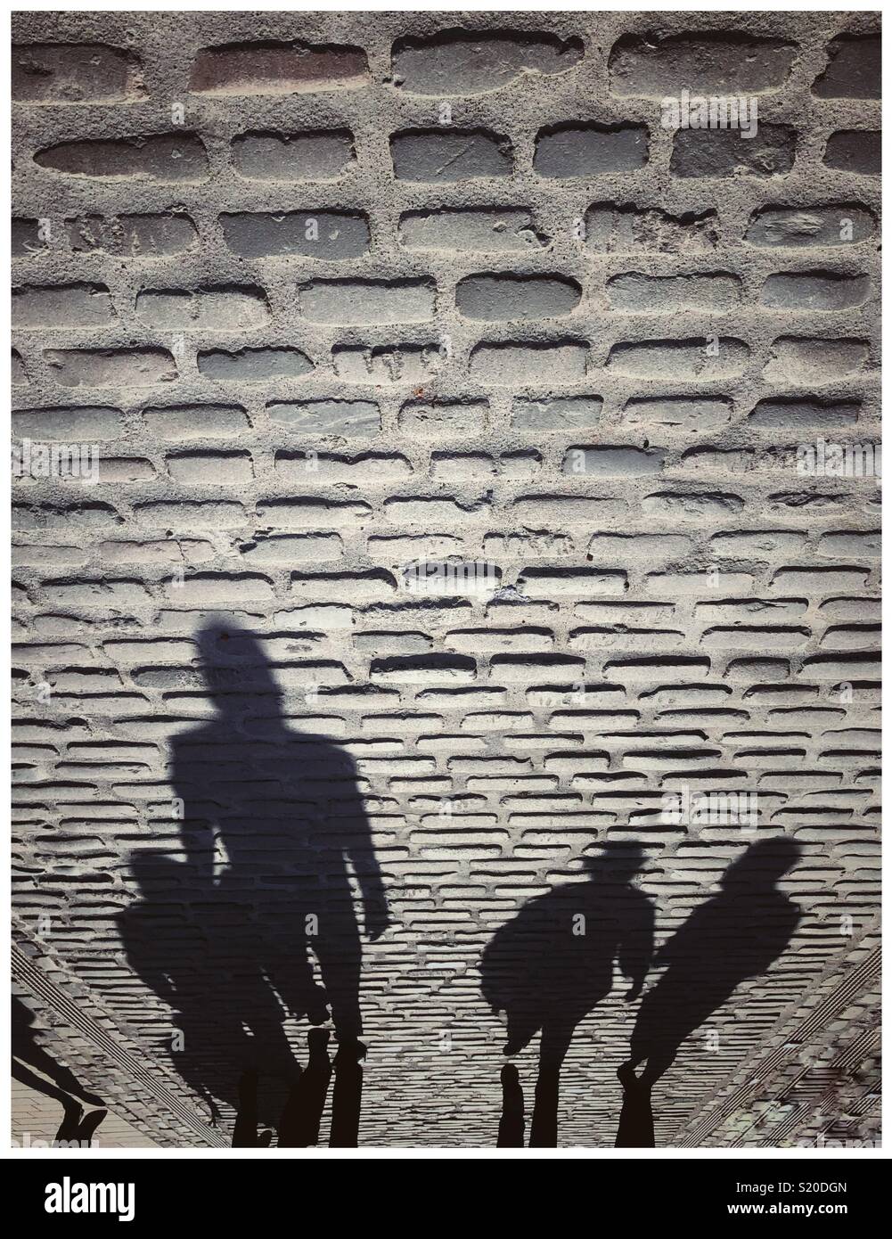 Silhouette Schatten von 4 Personen auf einer gepflasterten Straße Stockfoto
