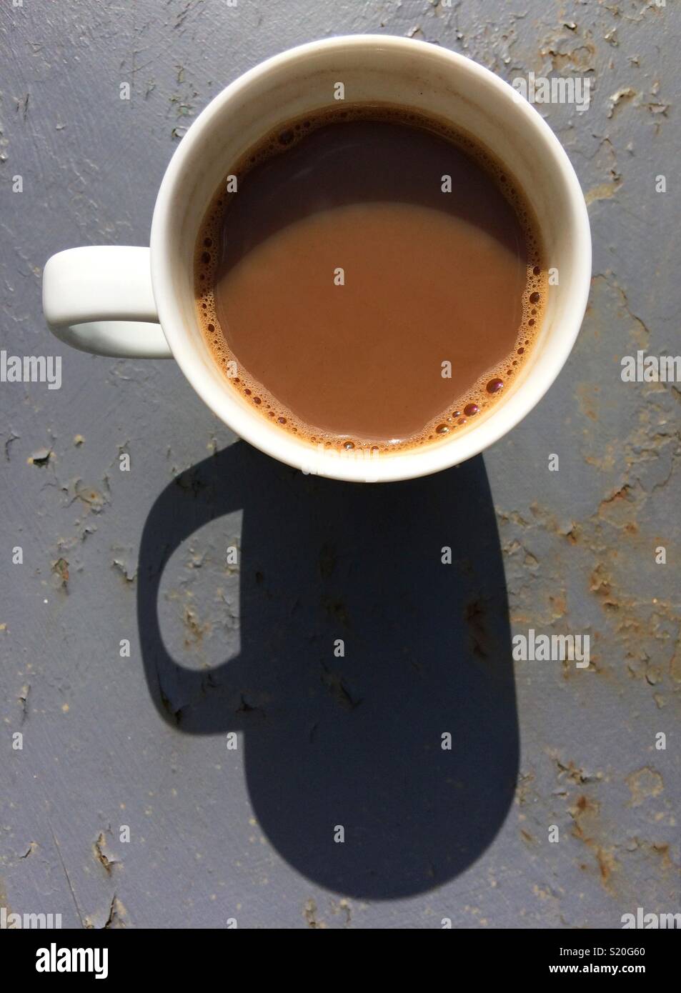 Tasse Kaffee Schuß von oben in der Sonne mit einem langen Schatten auf das grau lackiertem Metall Gartentisch Stockfoto