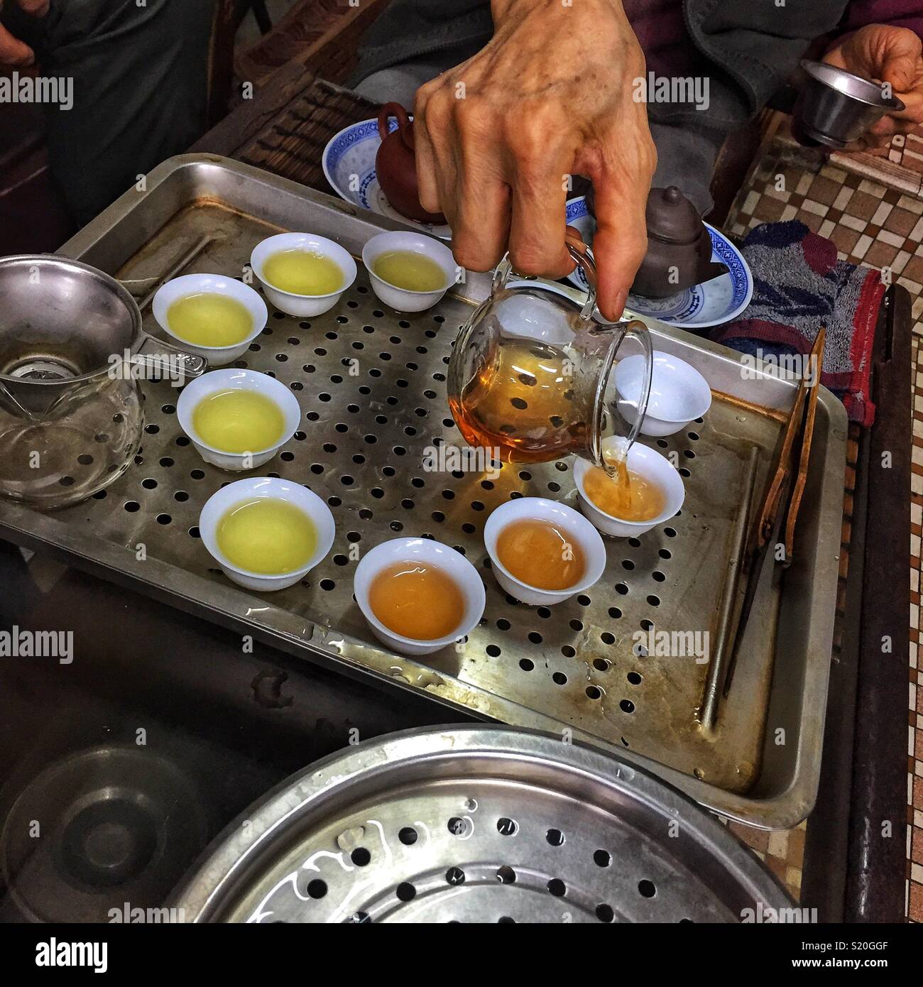 Chinesischer Tee wird in der traditionellen kleinen Tassen für die Verkostung in einem Geschäft in Sheung Wan, Hong Kong Island gegossen - Smartphone-aufgenommenes Stockfoto