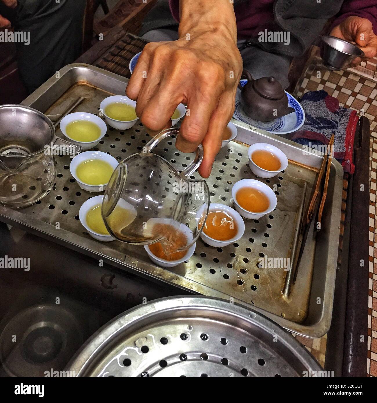 Chinesischer Tee wird in der traditionellen kleinen Tassen für die Verkostung in einem Geschäft in Sheung Wan, Hong Kong Island gegossen - Smartphone-aufgenommenes Stockfoto