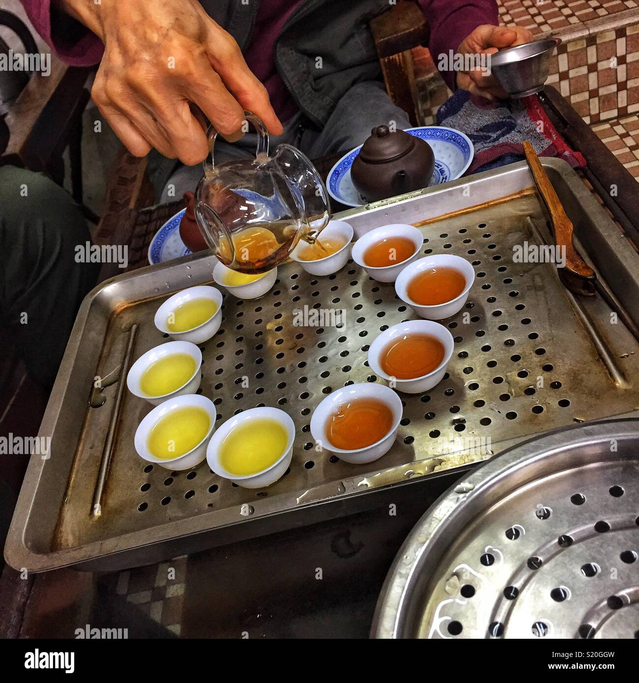 Chinesischer Tee wird in der traditionellen kleinen Tassen für die Verkostung in einem Geschäft in Sheung Wan, Hong Kong Island gegossen - Smartphone-aufgenommenes Stockfoto
