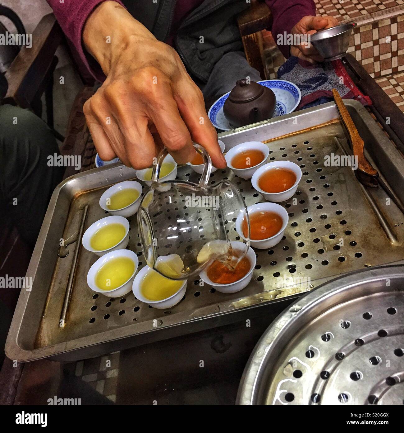 Chinesischer Tee wird in der traditionellen kleinen Tassen für die Verkostung in einem Geschäft in Sheung Wan, Hong Kong Island gegossen - Smartphone-aufgenommenes Stockfoto