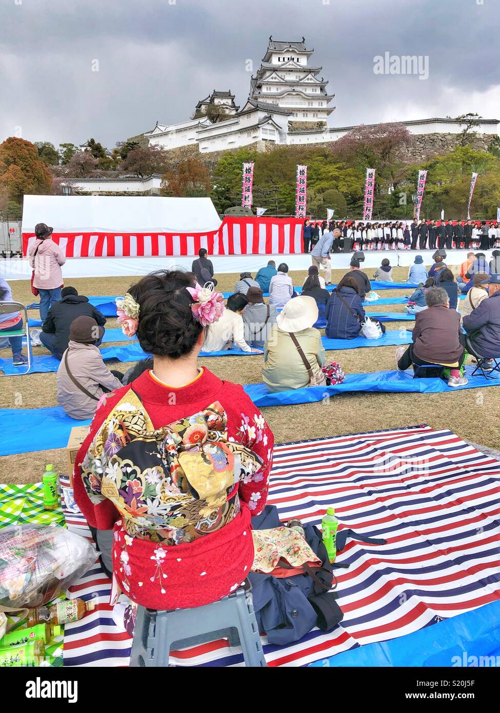 Frau in rotem traditionellen Kimono gekleidet ist, geniessen die jährliche Cherry Blossom Festival in Himeji, Japan. Stockfoto