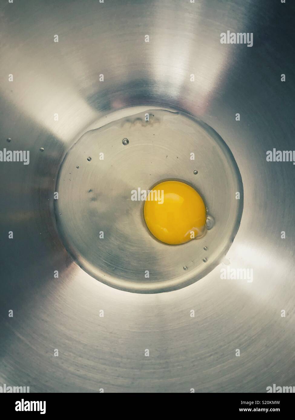 Eine gesprungene Ei in den Boden einer Schüssel aus rostfreiem Stahl - Smartphone-aufgenommenes Stockfoto