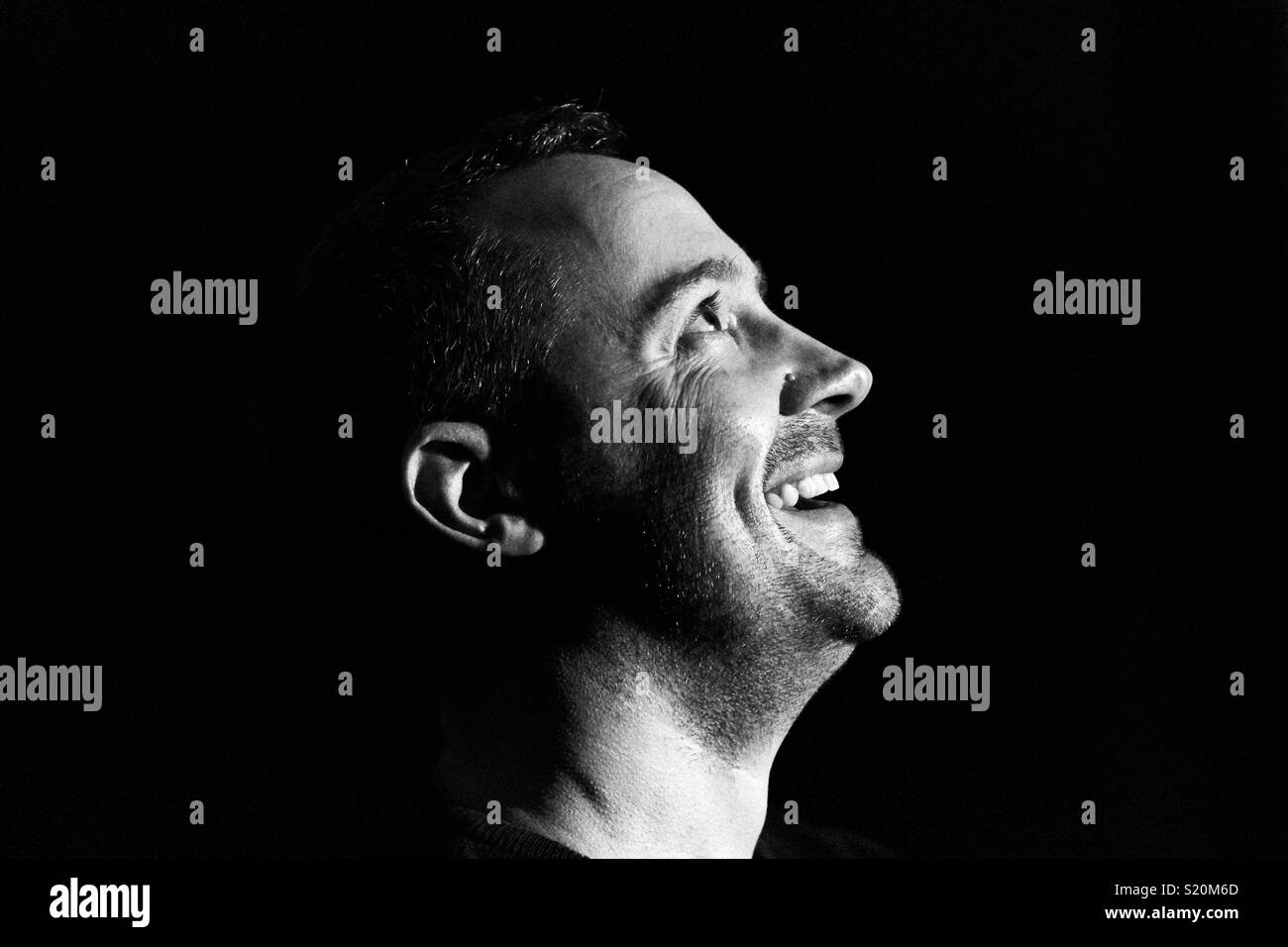 Ein Mann sieht glücklich und Lachen im Mondlicht. Low Key schwarz und weiß Profil Silhouette Foto auf schwarzem Hintergrund Stockfoto