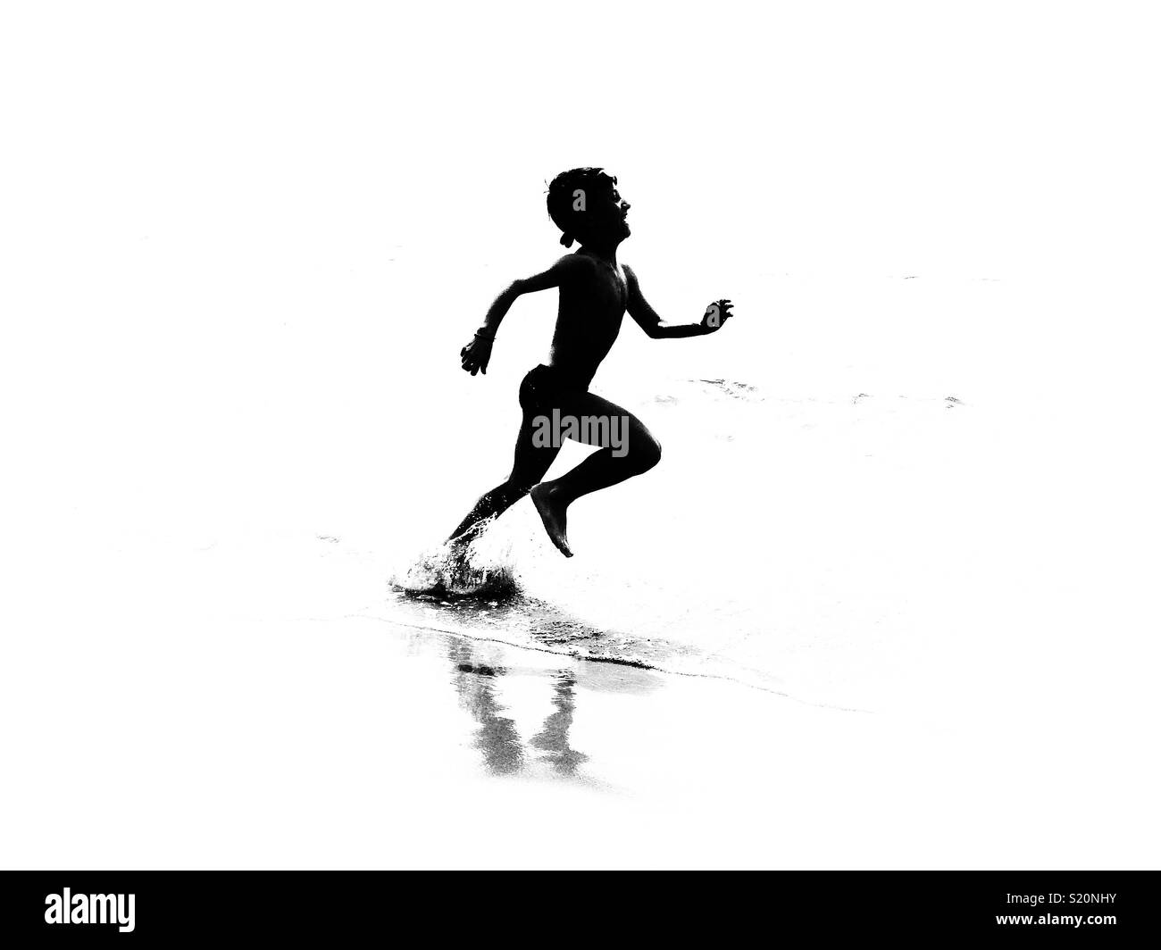 Junge ruuning am Strand. Silhouette Schwarz und Weiß Stockfoto