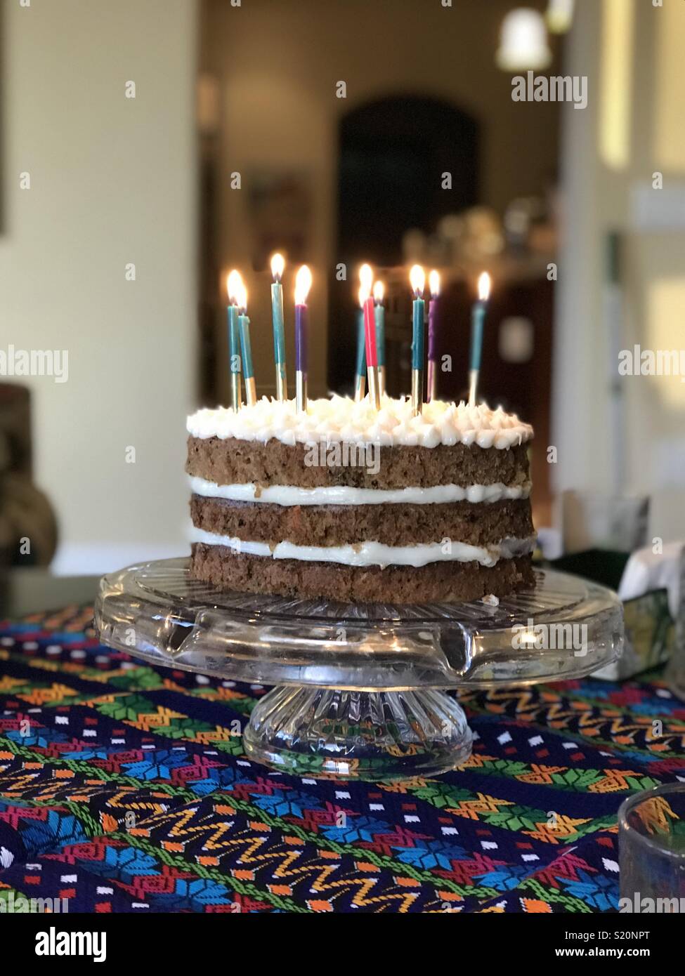 Bunte Karottenkuchen Geburtstag Kuchen mit zehn Kerzen angezündet und festlichen Tischdecke auf Crystal platter Stockfoto