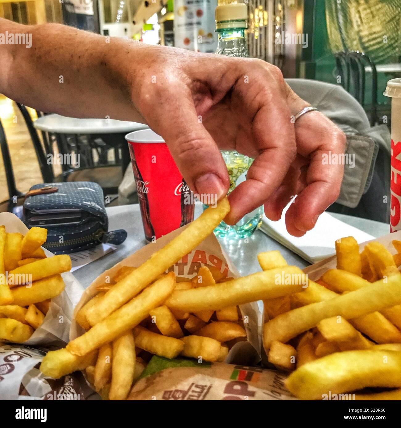 Frau Essen Pommes frites, während für einen verspäteten Flug im Abflugbereich der Flughafen El Altet, Alicante, Spanien warten Stockfoto