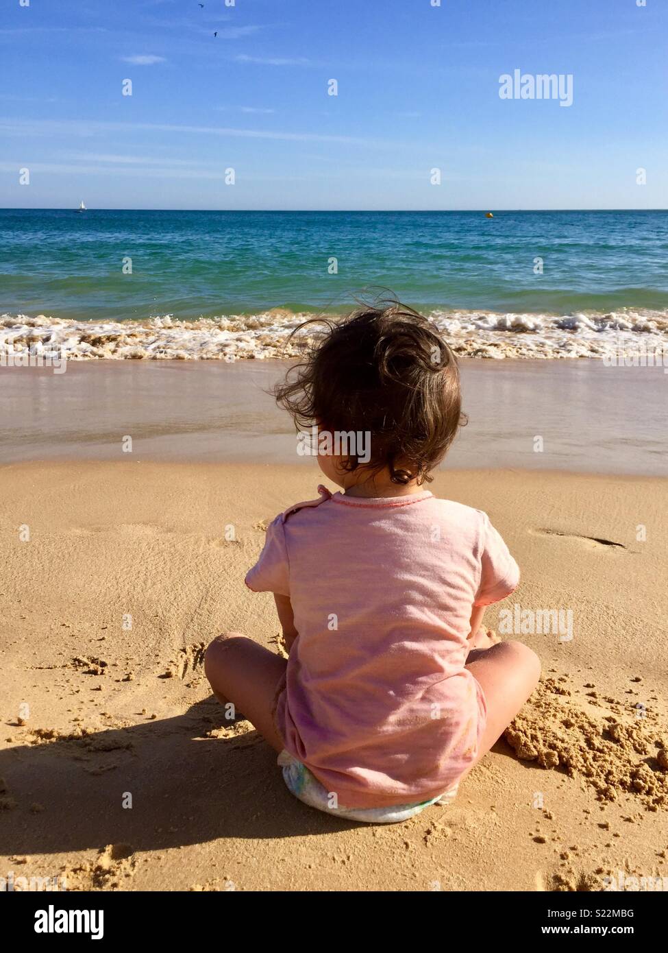 Kleinkind am Strand mit Blick auf das Meer Stockfoto