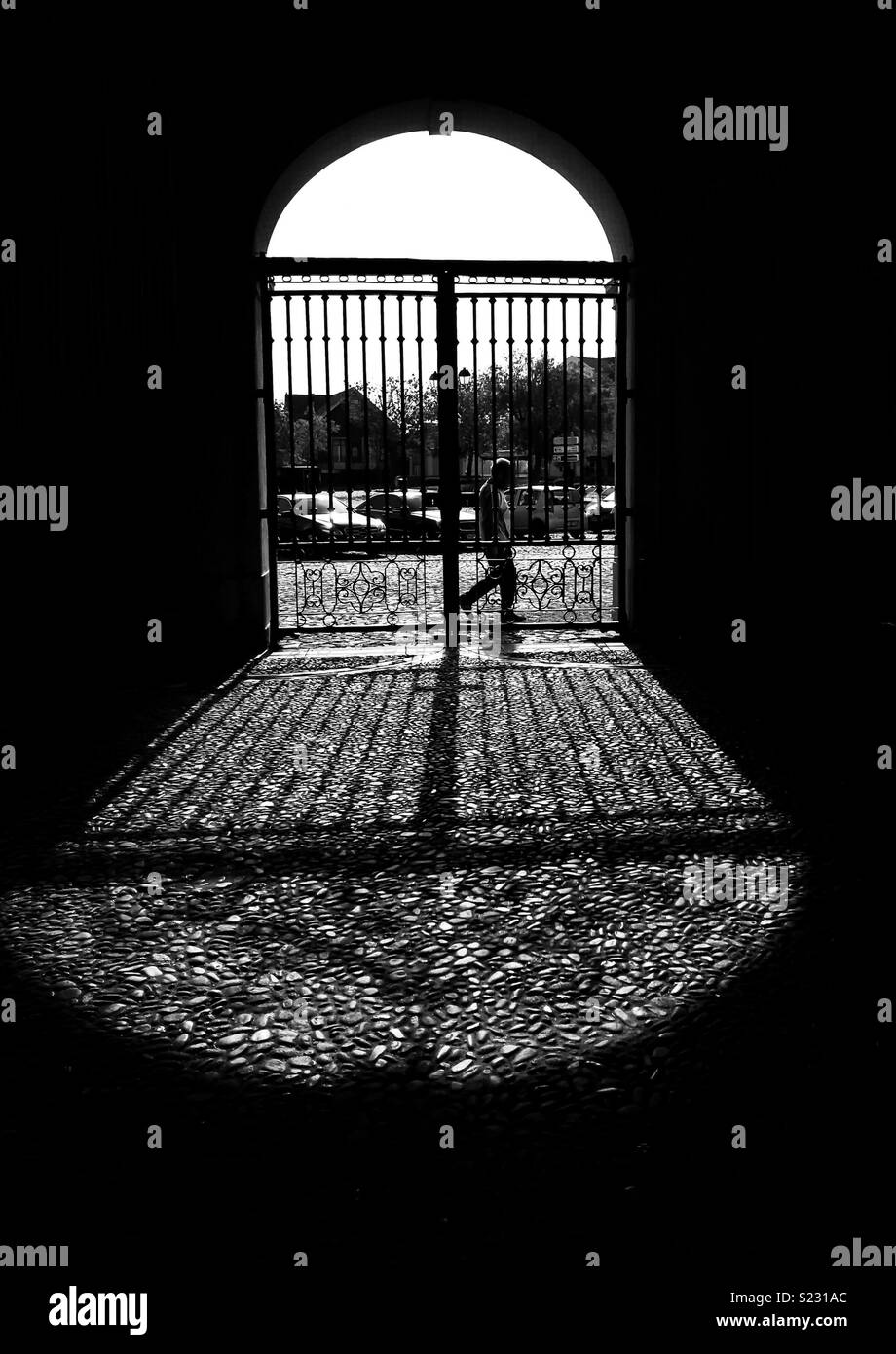 Silhouette der Mann hinter einem Tor und die Schatten auf den Boden werfen - Smartphone-aufgenommenes Stockfoto