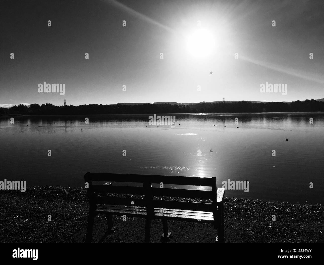 Helle Wintersonne über einem See, können Sie nur einen Heißluftballon unter der Sonne schwebenden von im Wind. Eine schöne Bank, die Welt zu sehen. Stockfoto