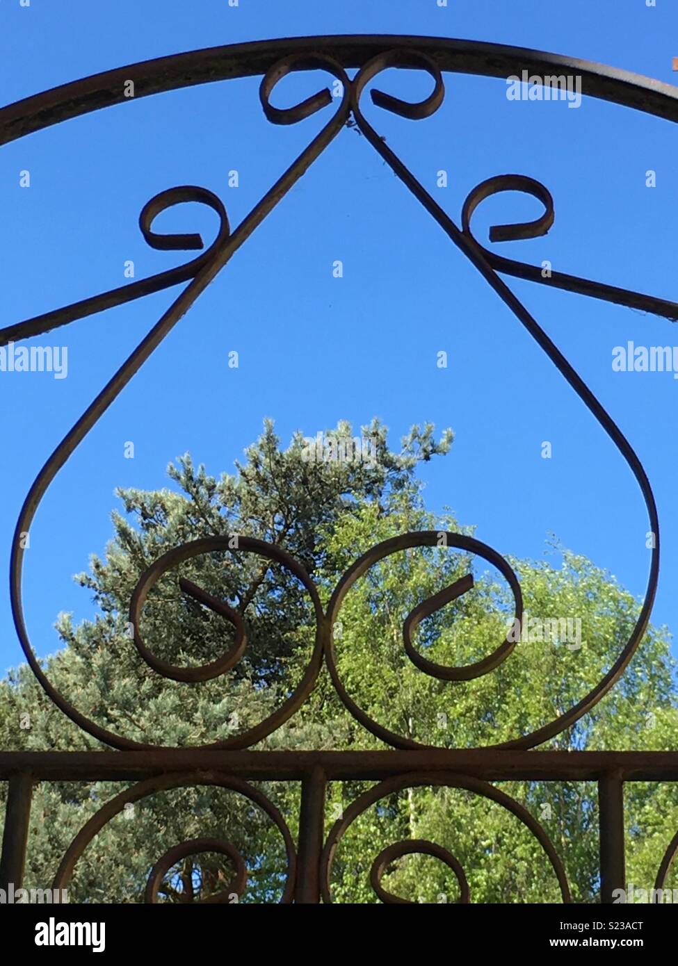 Schmiedeeisen herzen Tor an einem sonnigen Tag und an den Bäumen Stockfoto
